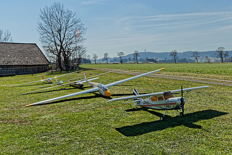 Segelflugmodelle und Schleppflugzeug auf der Wiese am Fluggelände